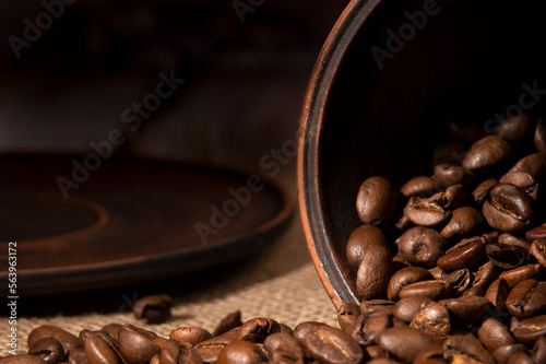 Coffee beans spilled out of the cup on the table in the kitchen 