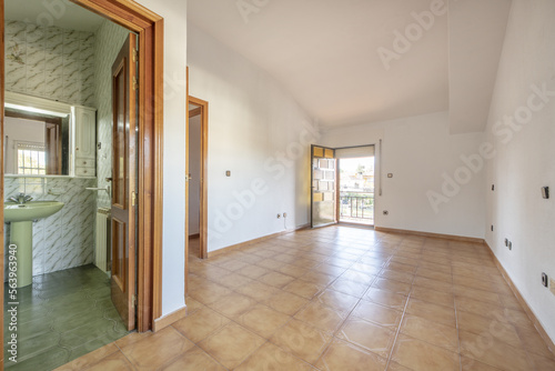 Large empty room of a house with a stoneware floor with its own bathroom and a terrace with a brown anodized aluminum door with translucent orange glass