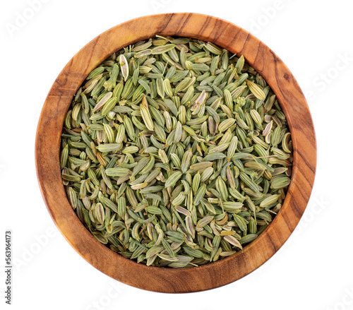 Fennel seeds in wooden bowl, isolated on white background. Green fennel grains. Spices and herbs. Top view.