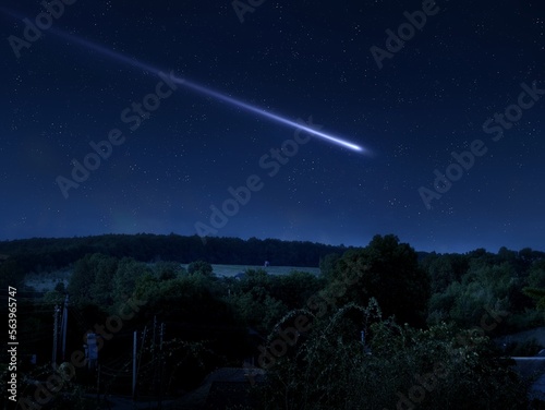 Falling star. A bright trail from a meteorite in the starry sky above the forest. A beautiful landscape with a meteor flash.
