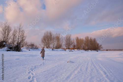 A young woman walks in the snow on a sunny frosty day, enjoying winter moments and nature, wearing winter clothes. Winter time concept, walk