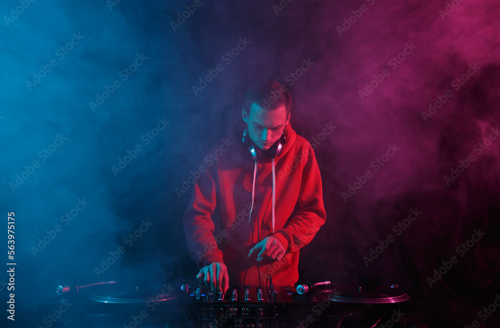 Disc jockey mixing hip hop music with vinyl records and sound mixer in