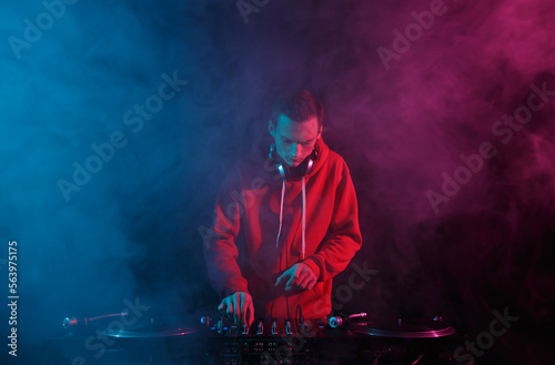Fotografia Disc jockey mixing hip hop music with vinyl records and sound mixer in smoke on stage