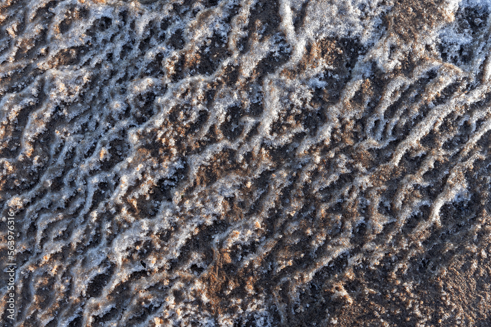 Wavy pattern of melting coastal ice mixed with sand. Abstract photo Wavy pattern of melting coastal ice mixed with sand. Abstract photo