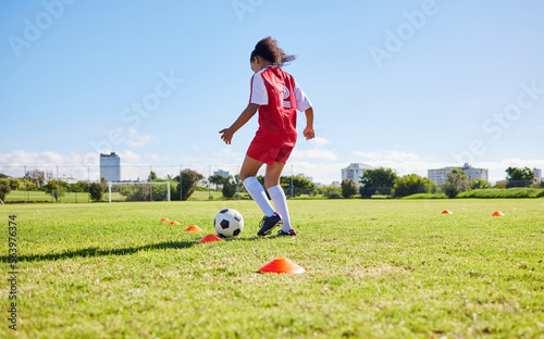 Football girl child, field and training for fitness, sports and development of balance for control, speed and strong body. Female kid, fast soccer ball dribbling or workout feet on grass for learning