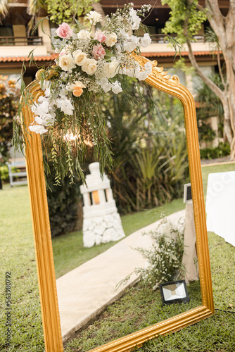 A welcome mirror board sign with a beautiful flower and rustic decoration, standing in front of wedding entrance.