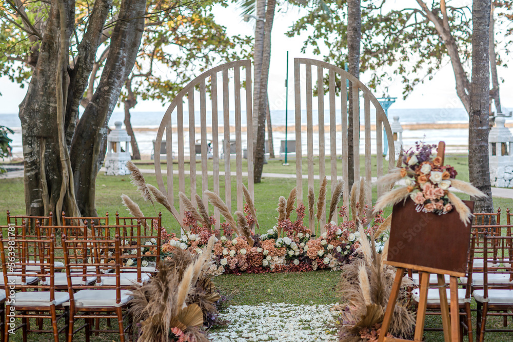 Beautiful outdoor wedding decoration with dry plants, flowers, candles and accessories in garden. Natural, shabby, boho wedding decor. Open air wedding banquet on green lawn with sea view