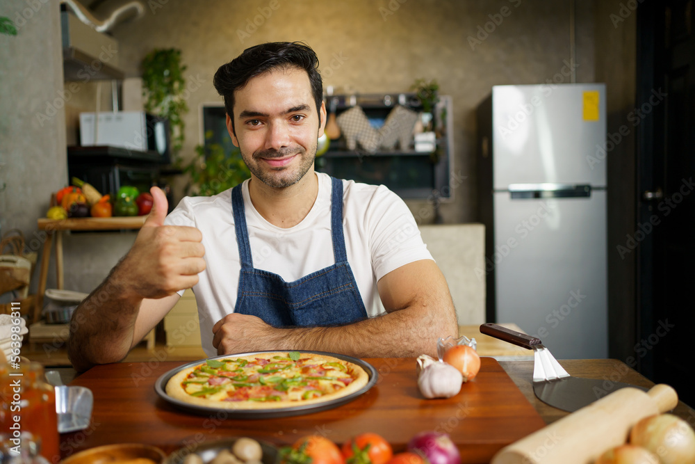 Happy cheerful handsome Italian chef showing a home made baked pizza to camera and smiling. Happy cheerful handsome Italian chef showing a home made baked pizza to camera and smiling.