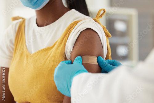 Vaccine, covid and a plaster on the arm of a black woman in a hospital for healthcare. Nurse, doctor and medical with a medicine professional in a clinic to apply a bandaid after corona vaccination photo