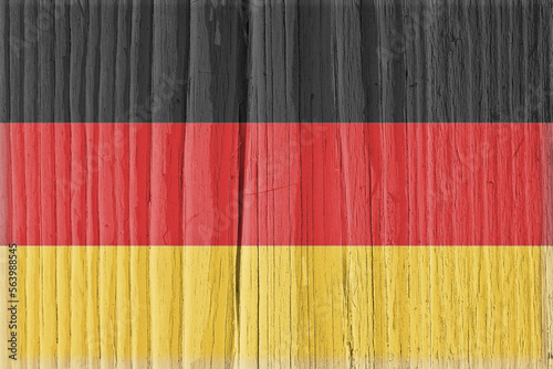 Flag of Germany on dry cracked wooden surface. German national symbol. Hard sunlight with shadows on old wood. Vintage background with faded pale vignetting