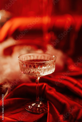 Coupe glass of champagne at red glamour background on valentines day photo
