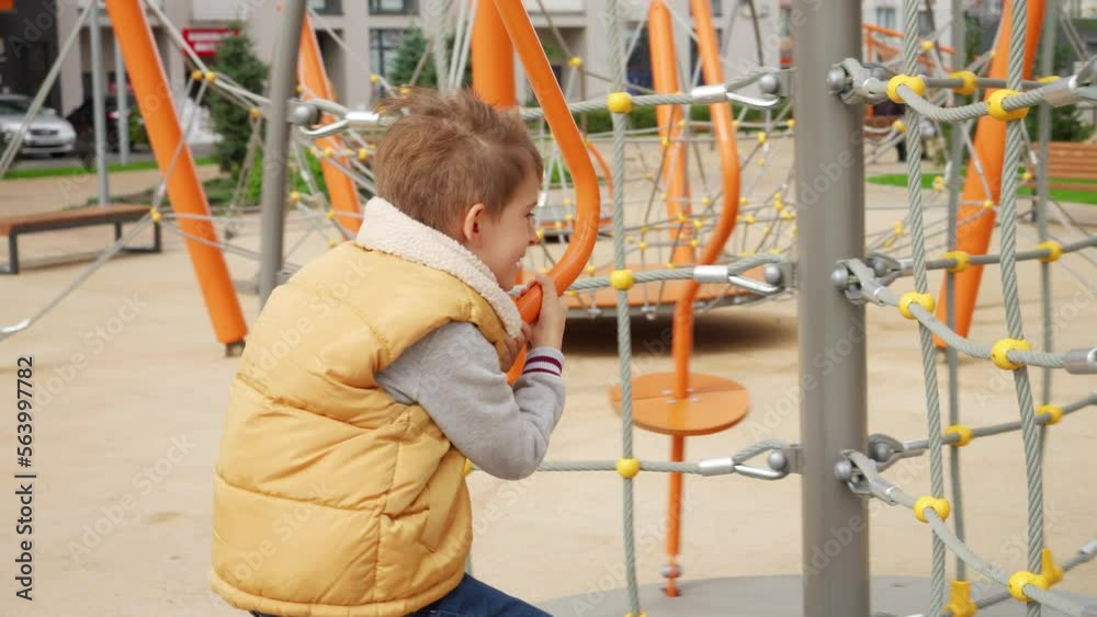 Cheerful smiling boy holding tight while spinning on merry-go-round carousel at public playground. Active child, sports and development, kids playing outdoors. Cheerful smiling boy holding tight while spinning on merry-go-round carousel at public playground. Active child, sports and development, kids playing outdoors.