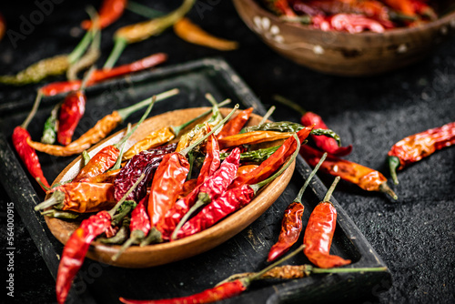 Fotografia Multicolored pods of dried chili peppers on a cutting board.
