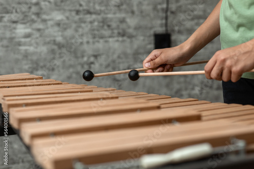 Hands of a young musician playing sticks on a wooden musical instrument xylophone, close-up, selective focus photo