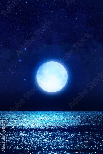 Full Moon with starry skies rising above ocean horizon.