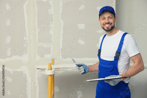 Professional worker with putty knives near wall. Space for text photo