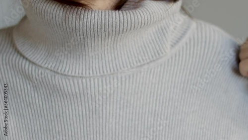 woman putting warm grey sweater pullover close up neck video slow motion autumn season.girl in wool clothes ready cold weather