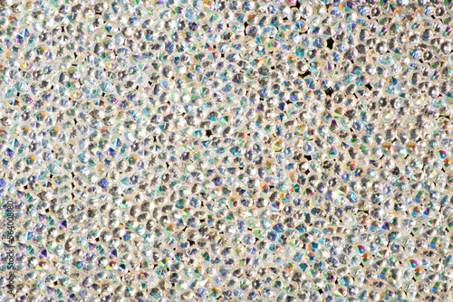 Abstract rhinestones background. Texture of rhinestones illuminated with whitr light. Multi-colored shine diamonds. Close up. Flares on glass photo