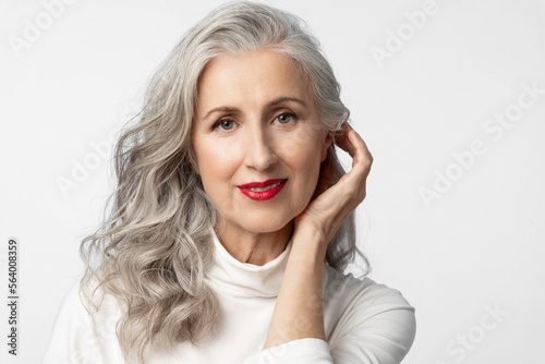 Fotografie Elegant mature woman with a well-groomed face, beautiful hair styling and makeup