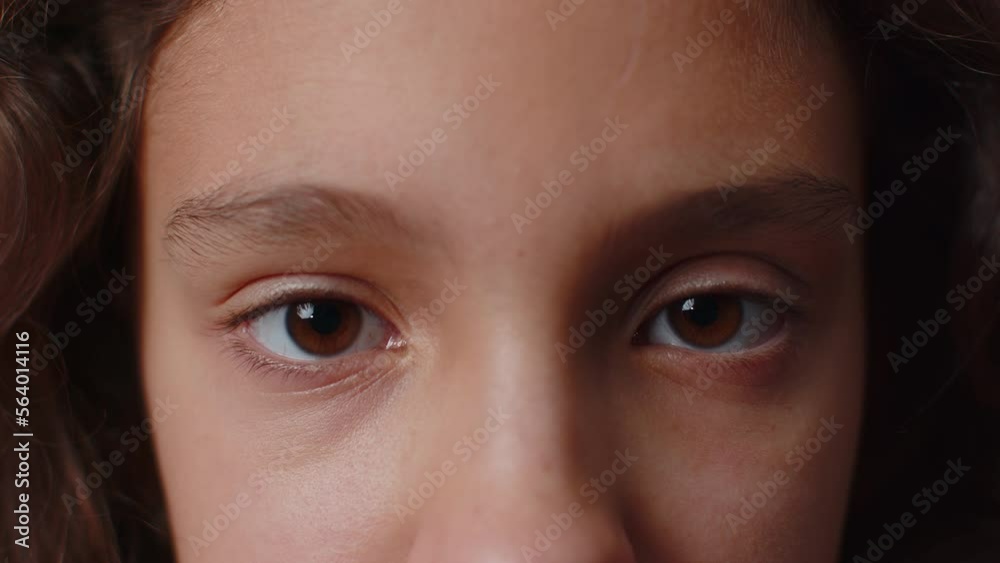 Extreme close-up macro portrait of smiling girl face. Teen beautiful kid's eyes, looking at camera. Brown eyes of brunette female child model. Young positive cute children opening wide her closed eyes