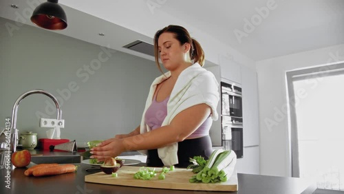 Attractive young woman is chopping vegetables in the kitchen