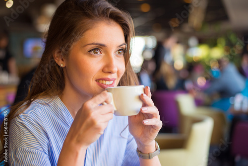 Young smiling woman drinking coffee in the coffee shop