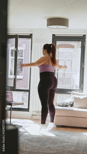 Vertical view of the body positive woman jumping at home at the floor