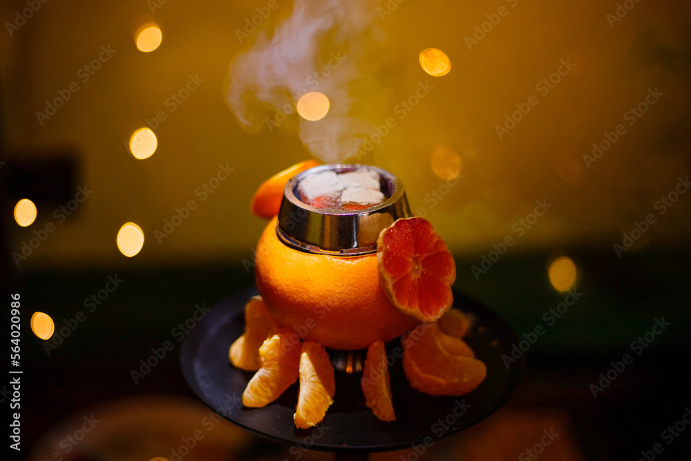Hookah on orange with smoke, with tangerine slices . High quality photo. Close-up photo
