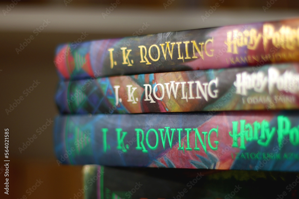 Fototapeta premium Split, Croatia - January 15, 2023: Stack of fantasy books by famous author J. K. Rowling. Bookshelf in the background. Selective focus.