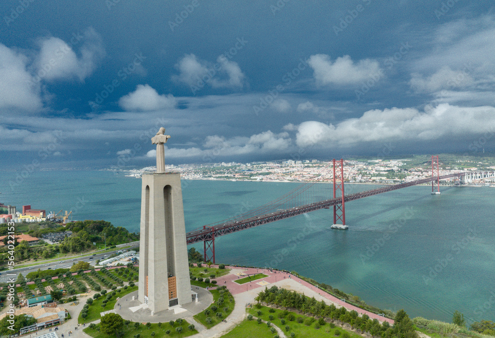 Sanctuary of Christ the King. Catholic monument dedicated to the Sacred Heart of Jesus Christ overlooking the city of Lisbon in Portugal. The 25 April bridge (Ponte 25 de Abril) in background