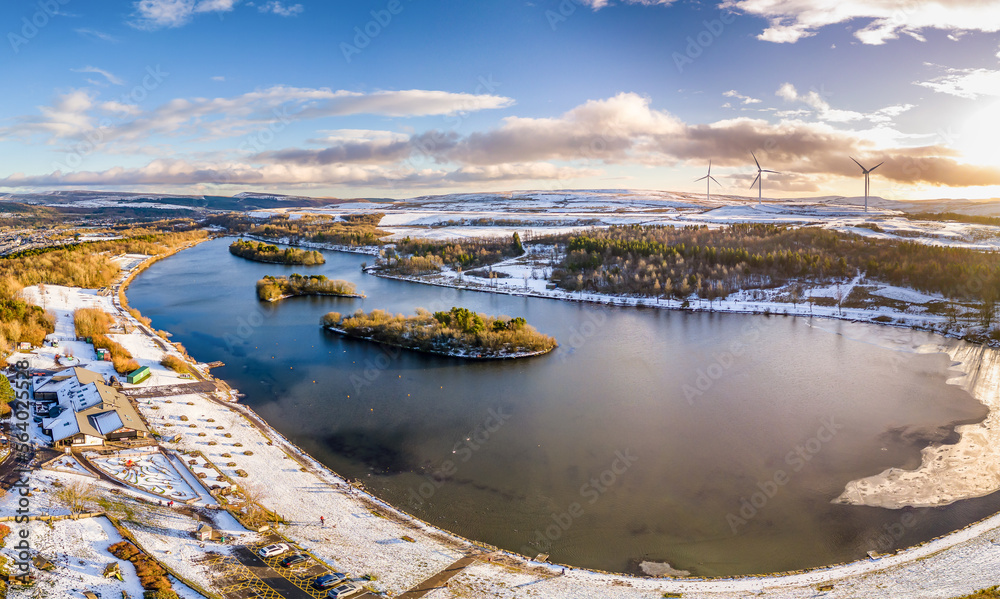 Panoramic aerial view of a semi-frozen lake surrounded by snow
