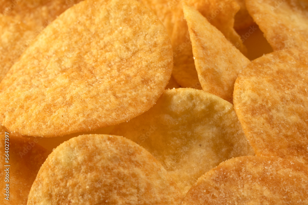 Potato chips scattered on the table close-up on a yellow background. Food with elevated cholesterol levels Potato chips scattered on the table close-up on a yellow background. Food with elevated cholesterol levels