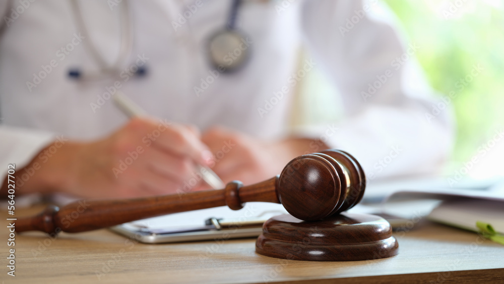 Wooden judge gavel on medical clinic desk and doctor doing