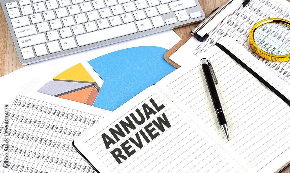ANNUAL REVIEW text on notebook with chart and keyboard ANNUAL REVIEW text on notebook with chart and keyboard