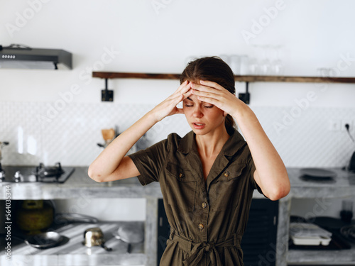 Portrait of a sad tired woman with a sore head in the kitchen, domestic problems, unstable emotional state, onion tears