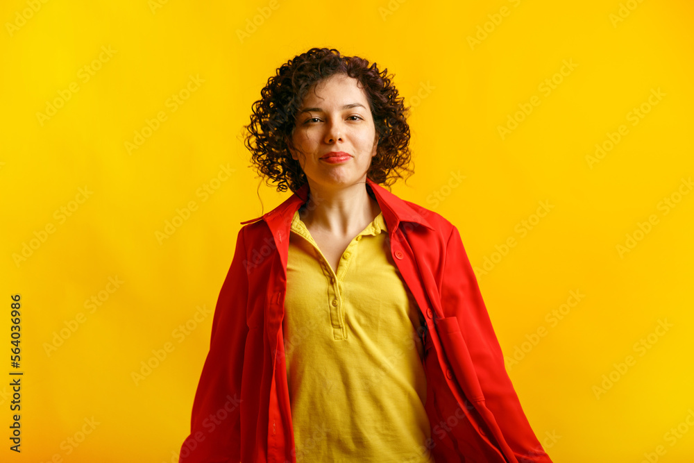 Curly cute girl smiling and jumping. Studio portrait of a pretty young caucasian woman on a bright yellow background. Positive active female in bright clothes. Copy space. Curly cute girl smiling and jumping. Studio portrait of a pretty young caucasian woman on a bright yellow background. Positive active female in bright clothes. Copy space.