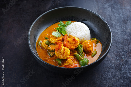 Traditional Thai kaeng phet red curry prawn with chili and basmati rice served as close-up in a Nordic design bowl photo