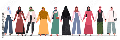 Group of young Muslim women in traditional hijabs and trendy clothes standing together and  holding hands. Concept of community, support, partnership, teamwork, social movement, unity, friendship and 