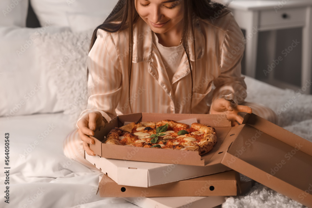 Young woman with boxes of tasty pizza in bedroom at night, closeup