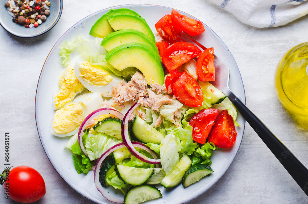 Tuna Salad, Healthy Food, Fresh Salad with Lettuce, Avocado, Cherries, Cucumber and Eggs on a Plate on Bright Background