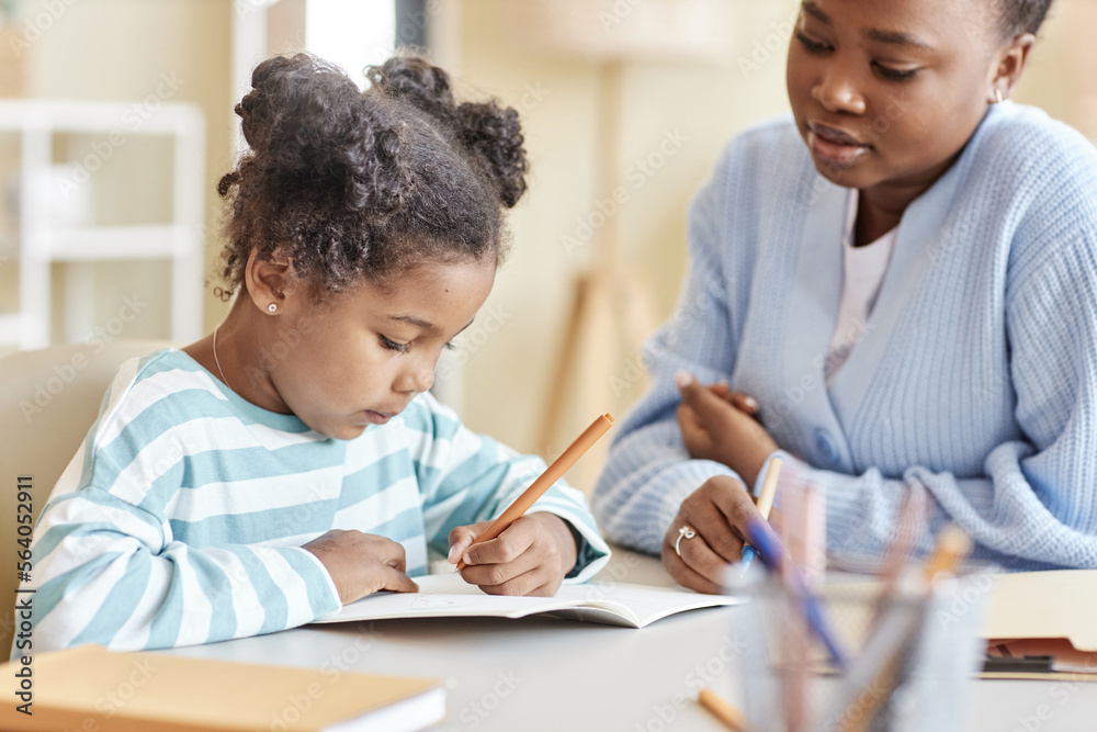 Side view cute black girl studying with tutor and writing in notebook Side view cute black girl studying with tutor and writing in notebook