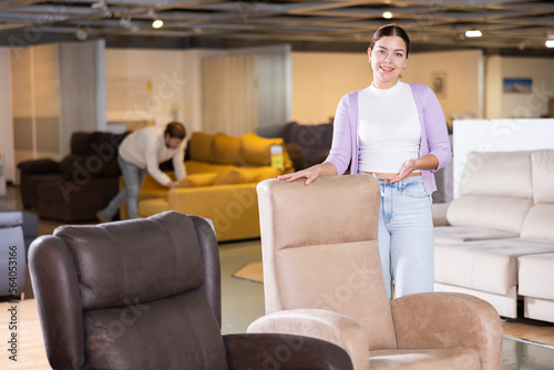 Furniture saleswoman offering armchairs in furniture store