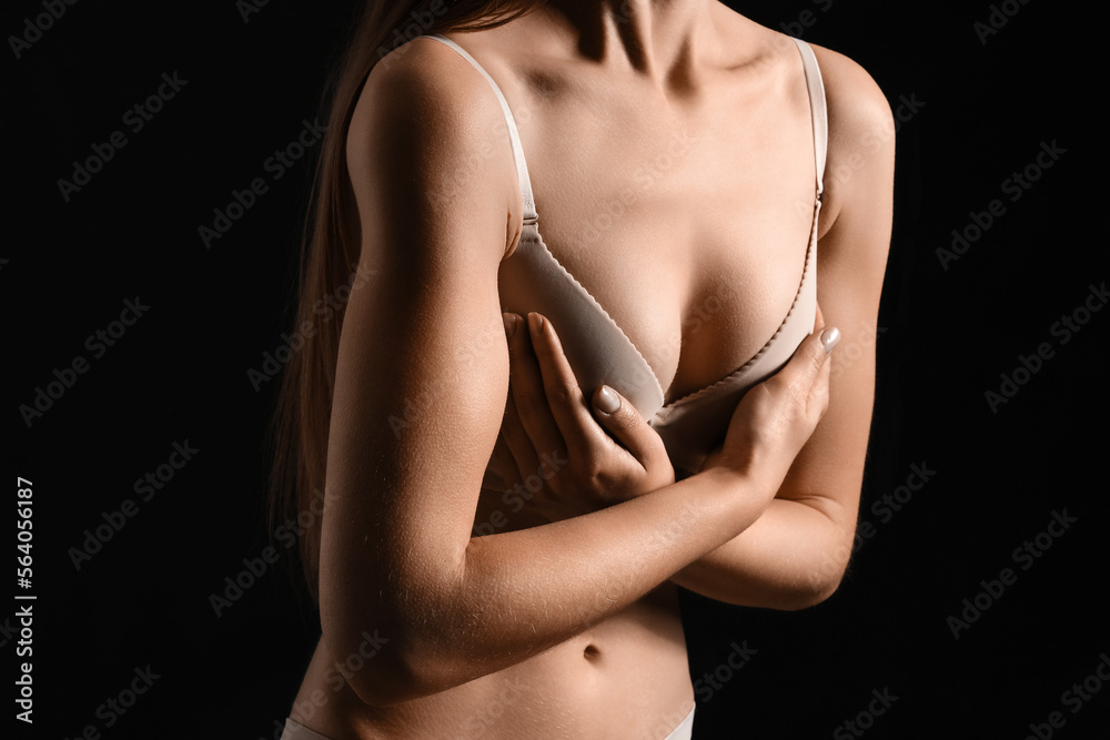 Naklejka premium Young woman in underwear on dark background. Breast cancer awareness concept