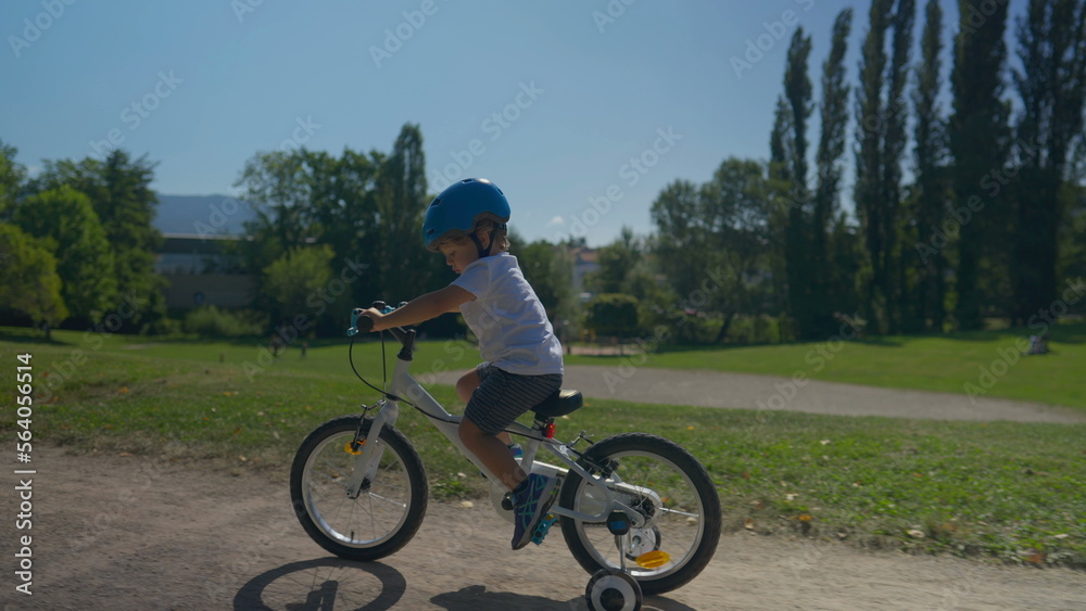 Child riding bike up a hill outside at park small boy rides bicycle