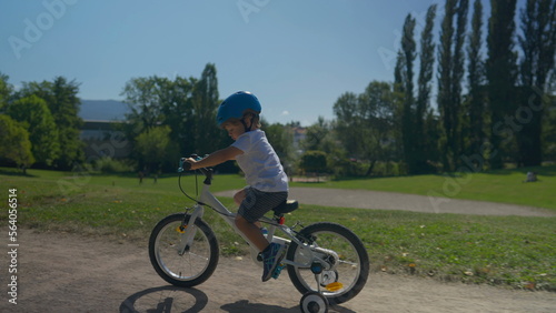 Child riding bike up a hill outside at park small boy rides bicycle