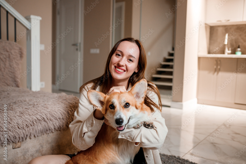 Attractive girl hug and play with corgi dog at home. Welsh Corgi Pembroke with his owner woman on the floor at living room Attractive girl hug and play with corgi dog at home. Welsh Corgi Pembroke with his owner woman on the floor at living room