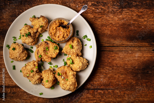 Cauliflower wings food. Pieces of cauliflower cooked in batter on a plate on a wooden background. Place for text.
