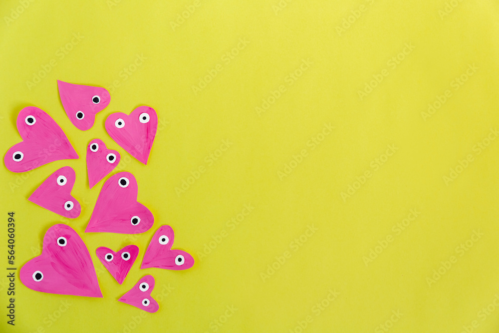 Hand made for Valentines or Mothers day. Hand-painted pink paper hearts with eyes on a yellow background. Flat lay. Space for text Hand made for Valentines or Mothers day. Hand-painted pink paper hearts with eyes on a yellow background. Flat lay. Space for text