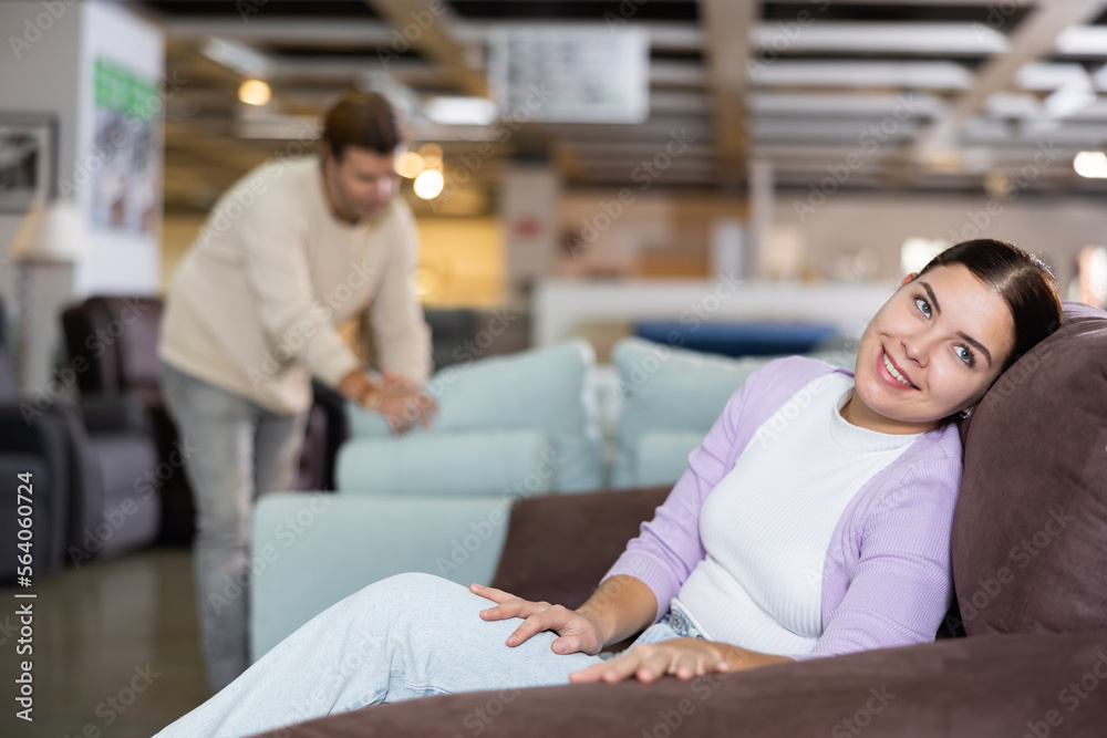 Fototapeta premium Woman trying out armchair in furniture showroom