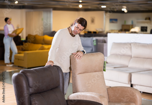 Man in a furniture store chooses an armchair for his home